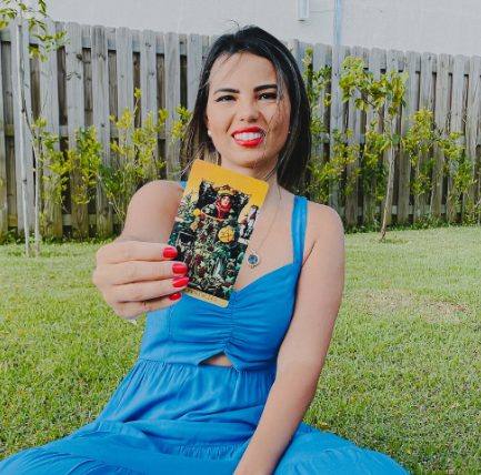 Juh Bueno segurando uma carta de tarot